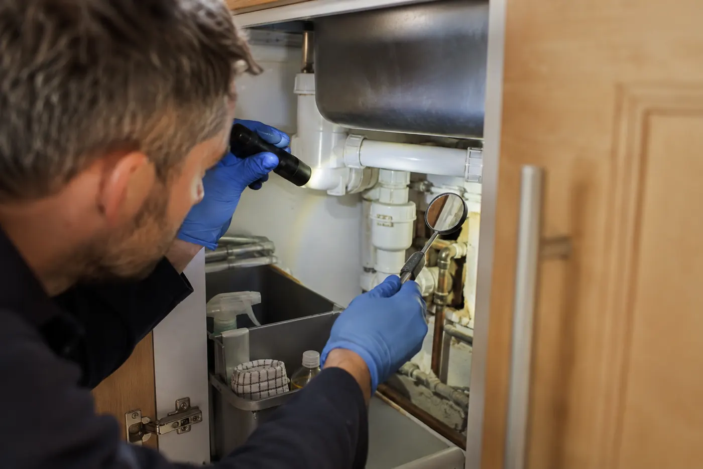 Inspection of pipe entry points beneath a kitchen sink